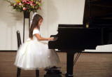 発表会で白いドレスで演奏する女の子の写真